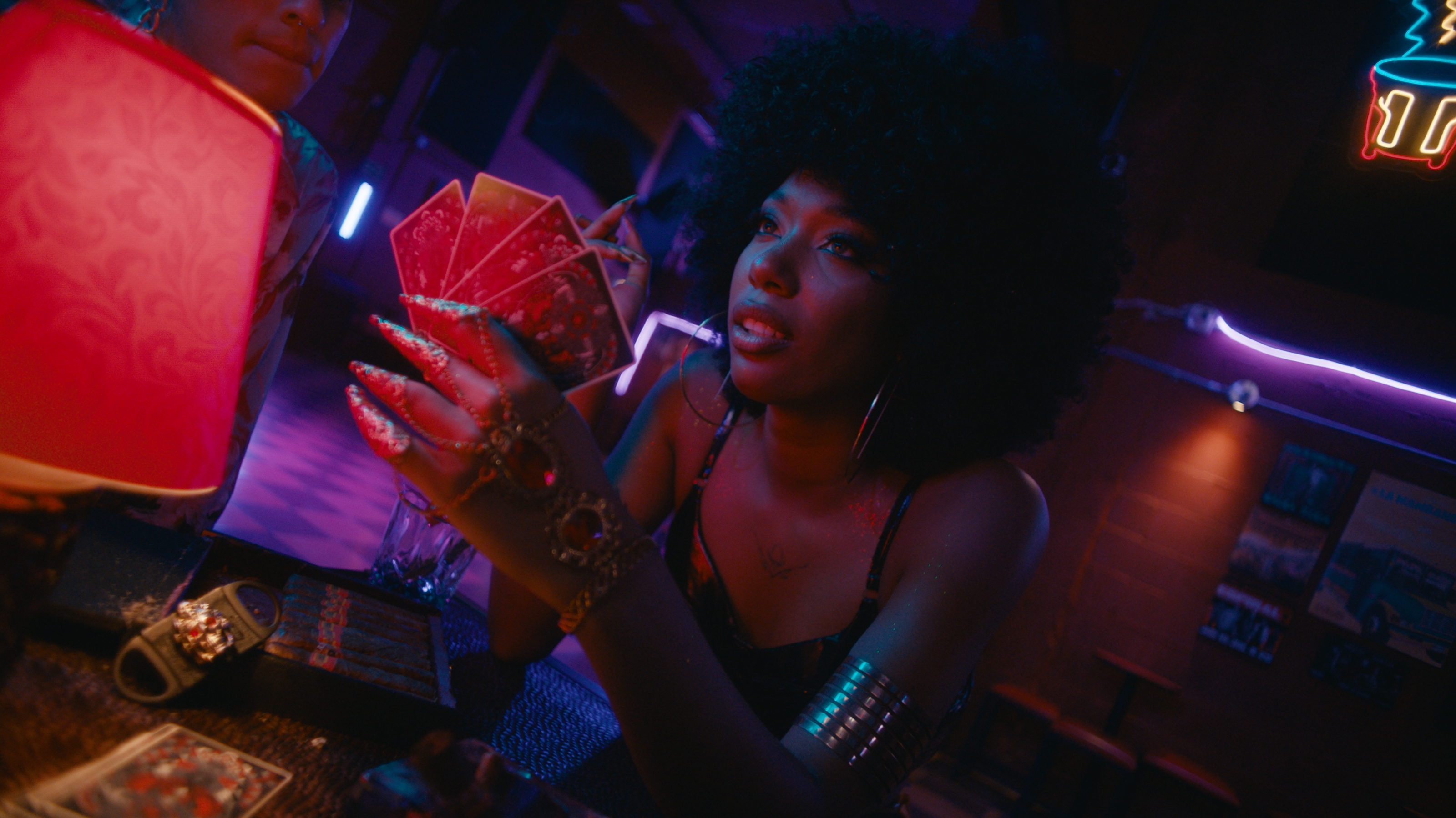 La Flaca con sus cartas en el bar iluminado de neón